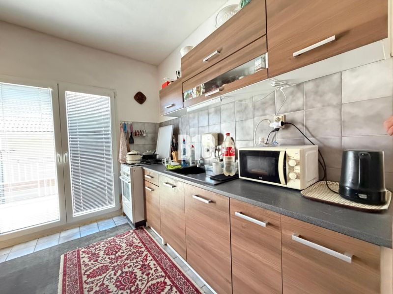 A kitchen in a family house with a kitchen unit and appliances, and a floor with a wooden decor.