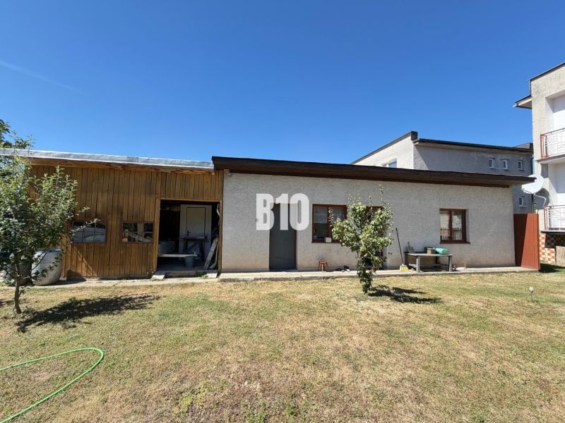 A family house in Kláštor pod Znievom with a wooden extension and a lawn on a sunny plot.