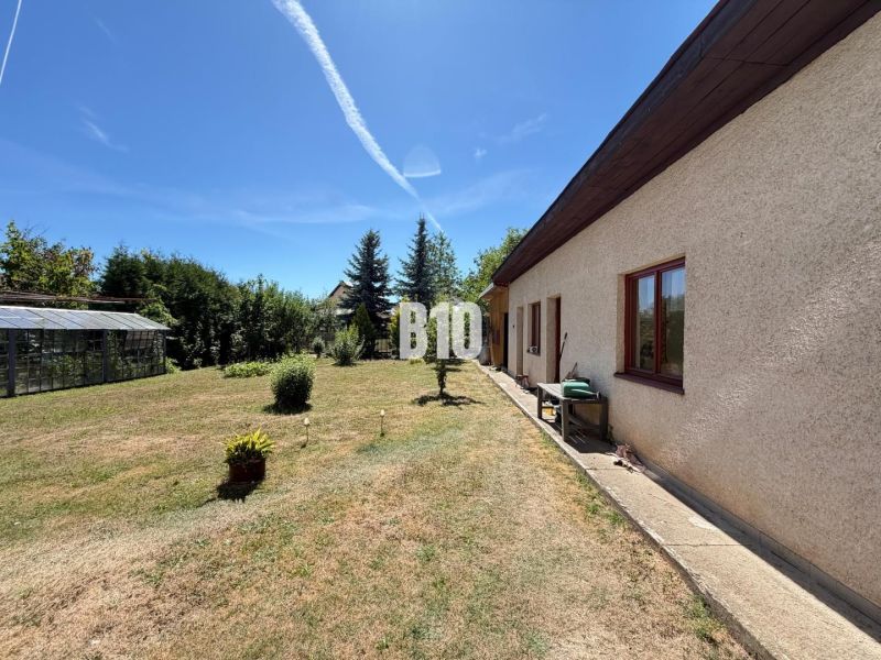 A family house in Kláštor pod Znievom with a garden and a greenhouse on a sunny day.