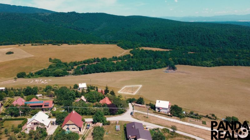 A rural view of residential plots in Podhradie surrounded by forests and meadows.