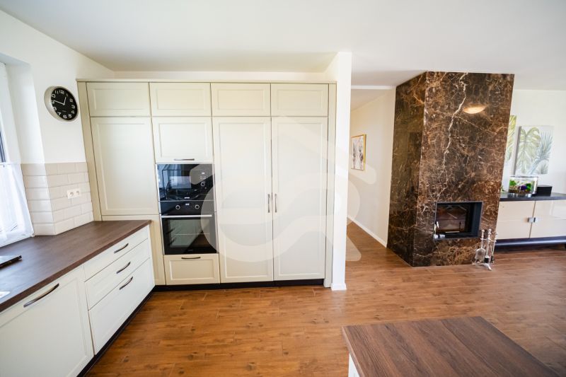 A kitchen in a family house with a fireplace wall and a wooden decor floor.