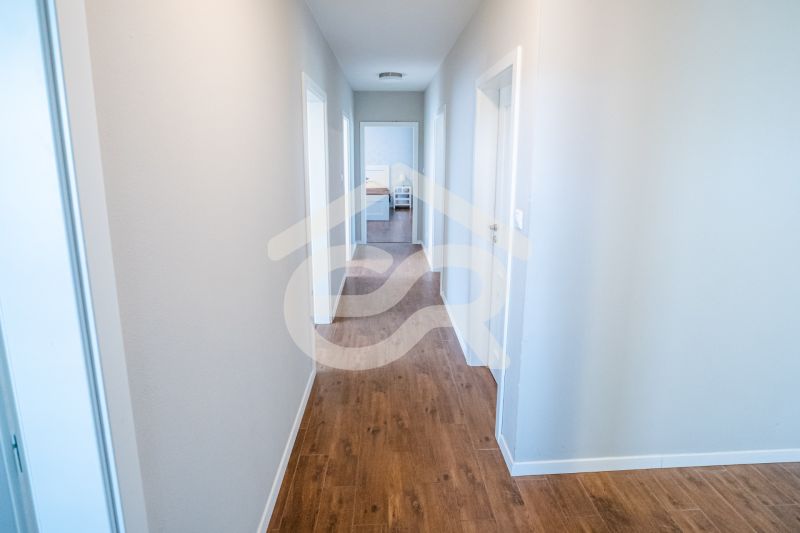 A hallway in a family house with a wooden decor floor and white walls.