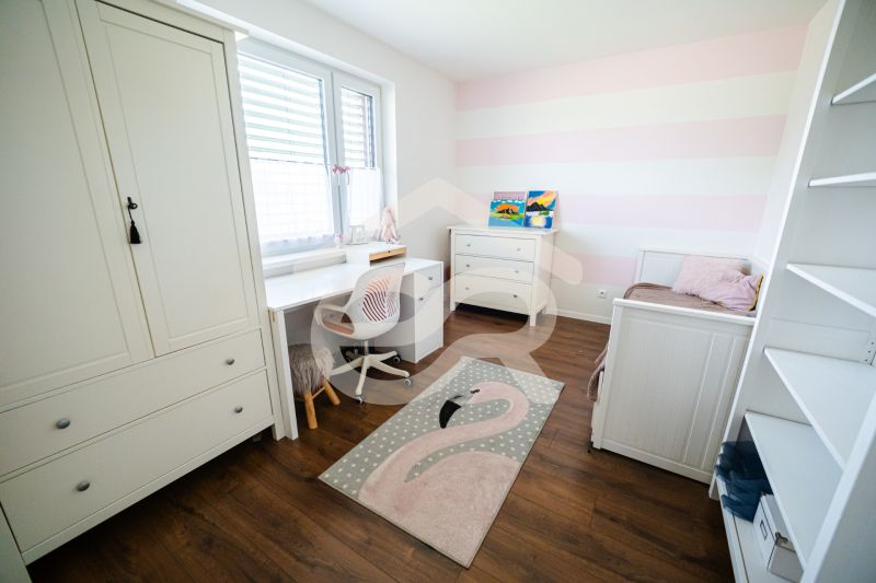 Children's room with white furniture and a wooden decor floor in a family house.