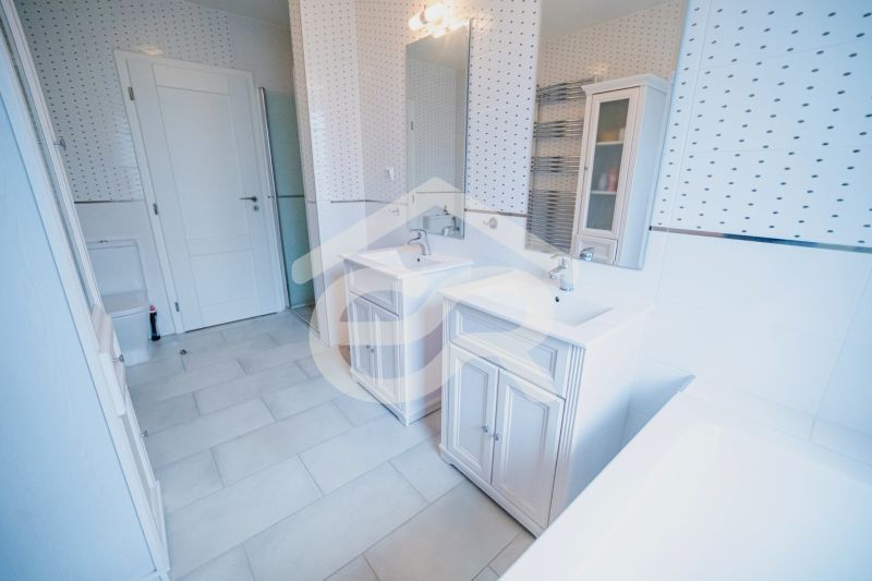 A bathroom with two sinks, a bathtub, and tiles in a family house.