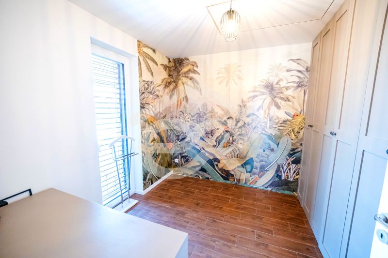 A room in a family house with exotic wallpaper and a wooden decor floor.