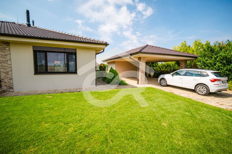 A family house on Družstevná Street in Vráble with a car and a covered parking space.