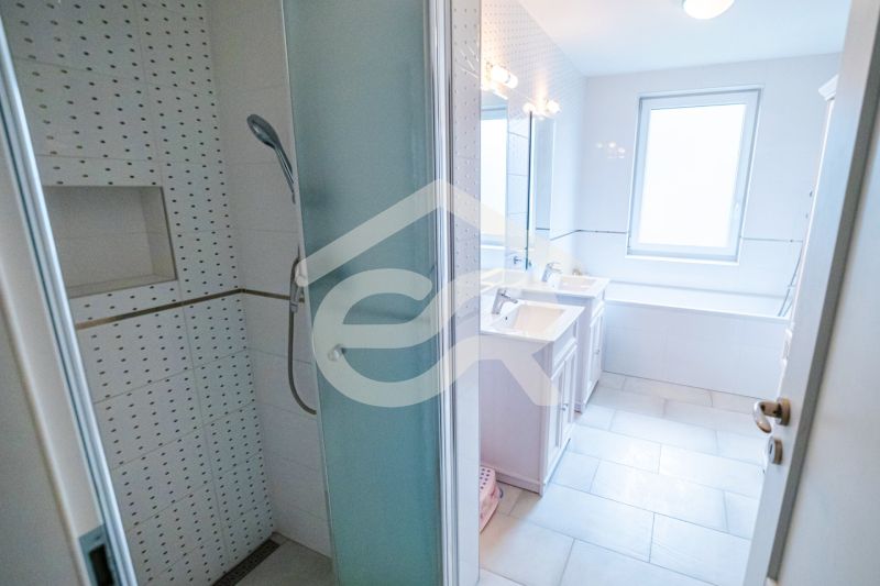 A bathroom in a family house with a bathtub, shower, and sinks.