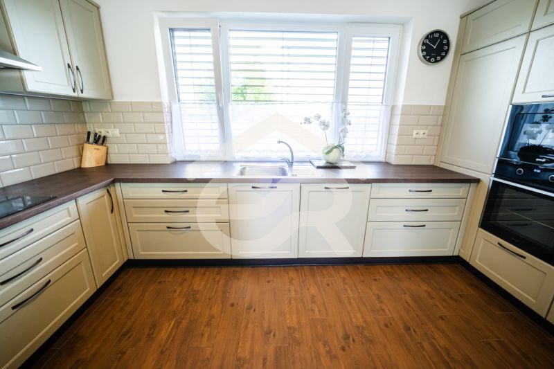 A kitchen in a family house with beige cabinets and a wood-patterned floor.