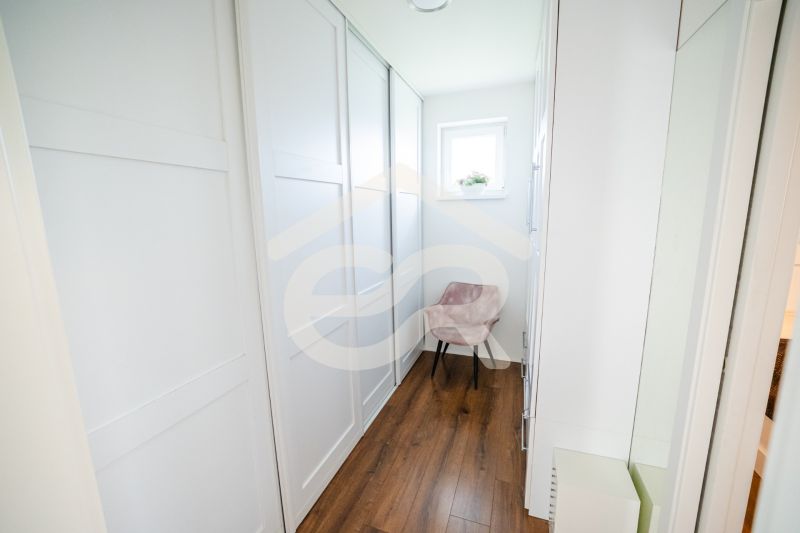 A narrow hallway in a family house with a wood-patterned floor and a window.