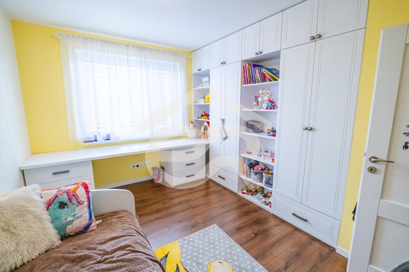 Children's room with a bed, shelving cabinet, and floor with wooden decor in a family house.