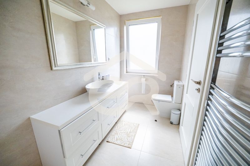 A bathroom in a family house with a white sink and a large mirror.