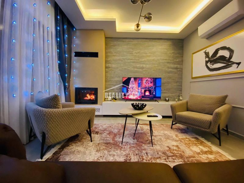 Living room with comfortable armchairs, decorative lights, and a fireplace in a family house.
