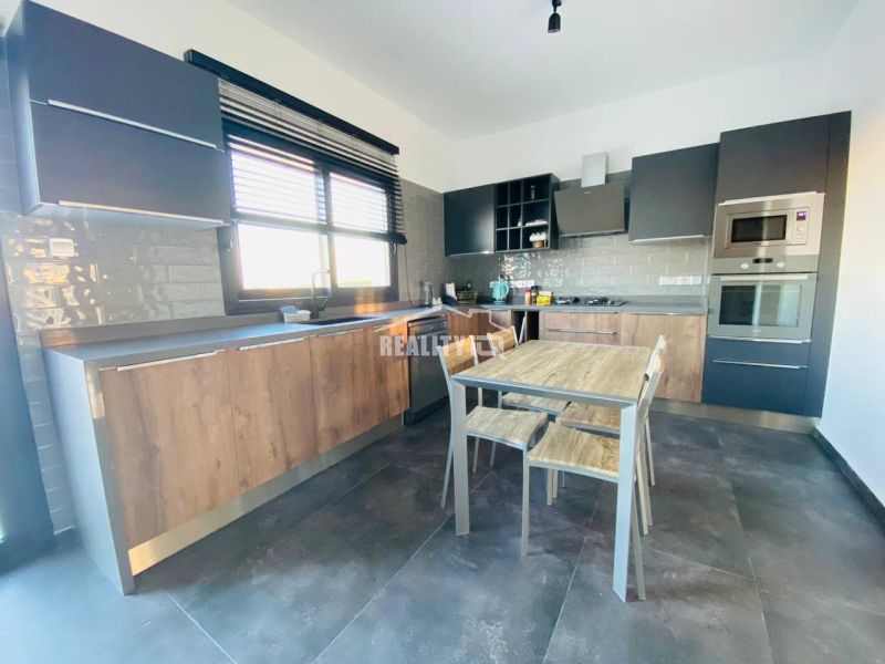 A kitchen with wooden decor, modern appliances, a spacious table, and gray cabinets.