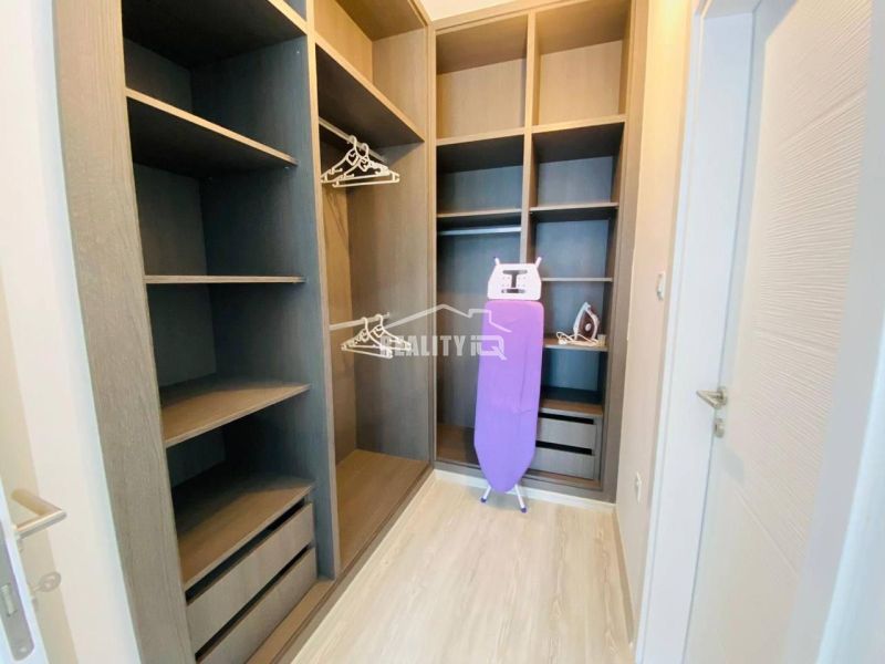A wardrobe in a family house with shelves, hangers, and an ironing board.