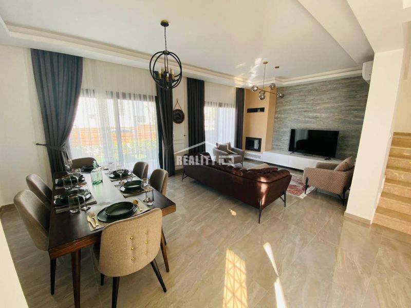 Living room with a dining table, sofa, and large TV in a family house.