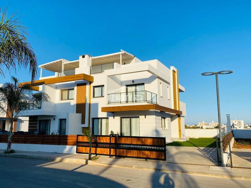 A family house in Yeni Boğaziçi with a white facade, wooden elements, and palm trees on the property.