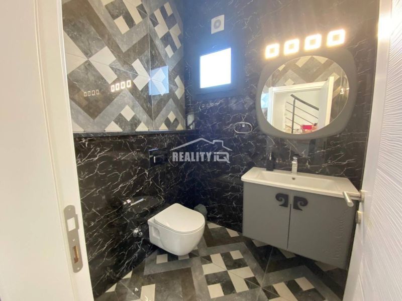 A bathroom in a family house with dark paneling and geometric patterns on the walls.