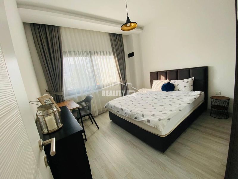 Bedroom with a bed, desk, and wooden decor flooring in a family house.