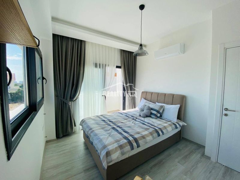 A bedroom with a large window, curtains, and a wooden decor floor in a family house.