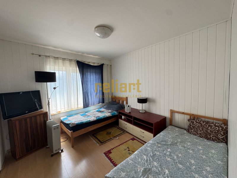 A bedroom in a family house with beds, a television, and a floor with a wooden decor.