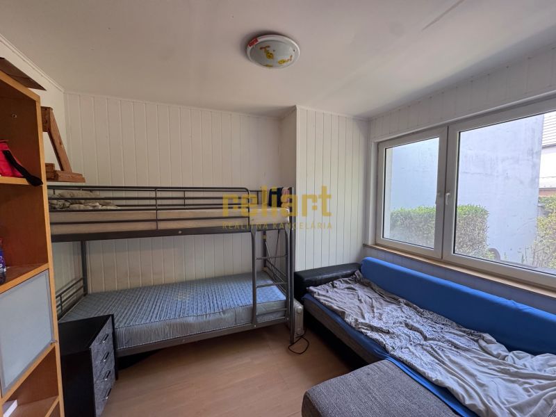 A room with a bunk bed, a sofa bed, and a shelving unit in a family house.