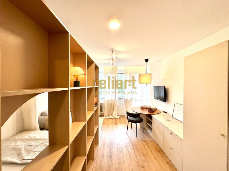 Interior of a 1-room apartment with a shelving partition and a floor with a wooden decor.