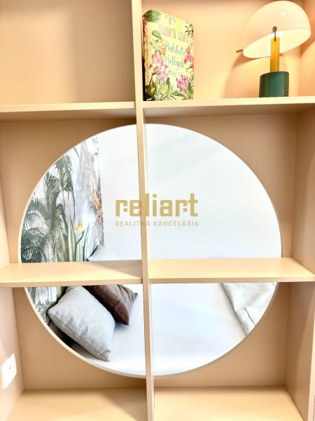 A mirror on a shelf with a book and a lamp in a studio apartment.