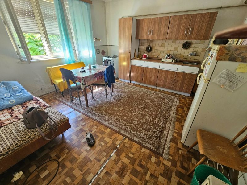 A kitchen in a family house with a dining table, kitchen unit, and floor with a wooden decor.