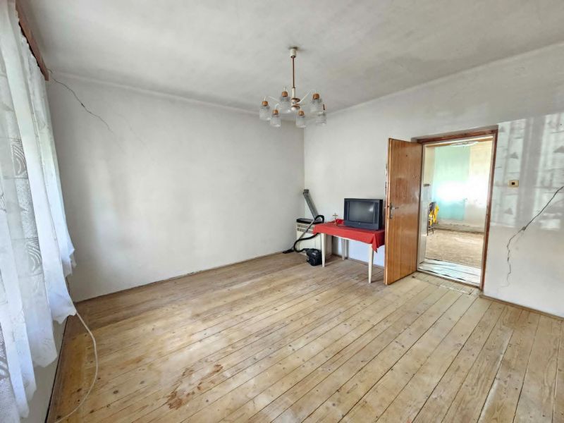 A room in a family house with a wooden decor floor, a television on the table.