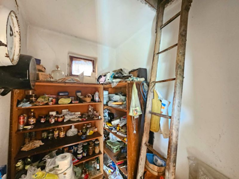 A shelf with groceries and a ladder in a room of a family house.