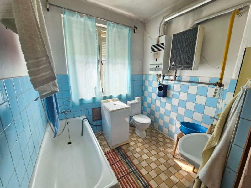 A bathroom in a family house with older light blue tiles and a bathtub.