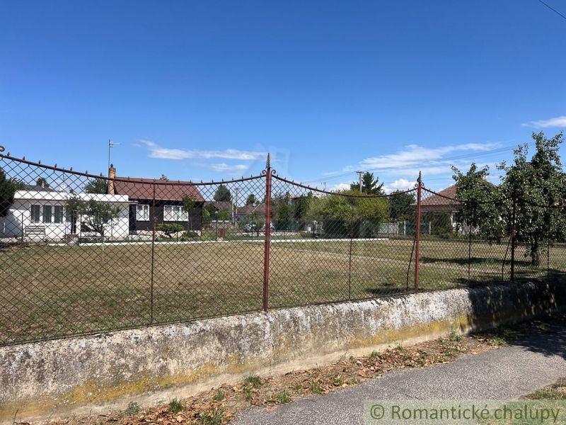A plot with an older house and trees in the gardens of Bernolákovo under the blue sky.