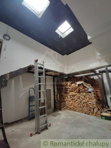 A family house with wooden beams and stored wood in the interior.