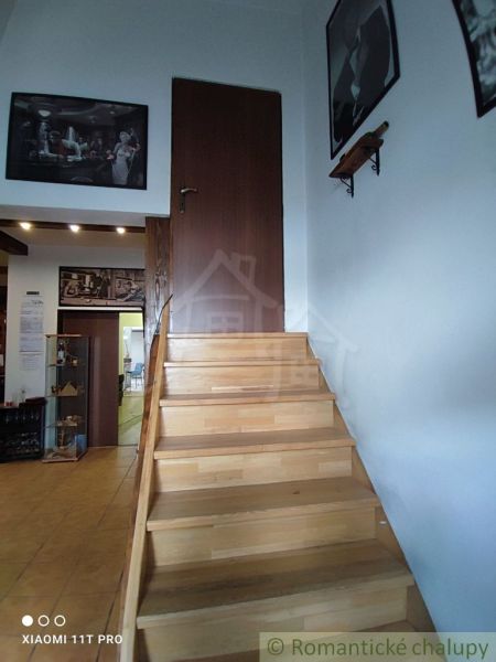 Staircase with a wooden decor floor and art paintings on the walls in a family house.