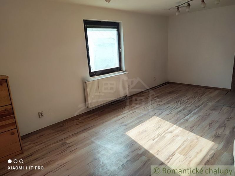 A room with a wooden decor floor and simple furniture in a family house.