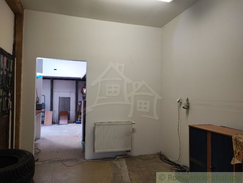 Interior of a family house with white walls, a radiator, and open doors.
