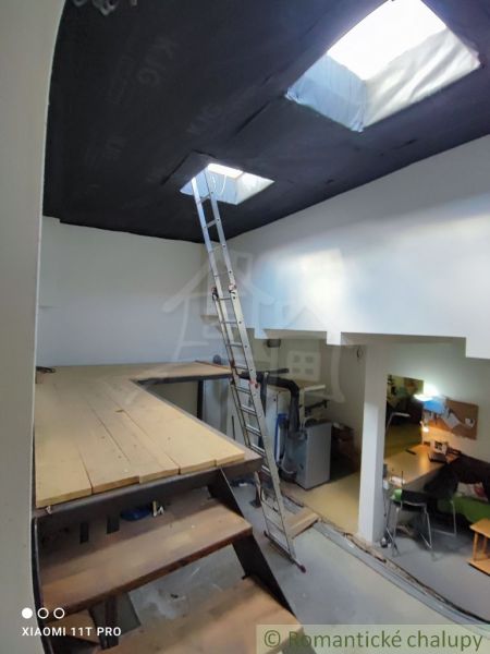 Attic with a ladder and a floor with wooden decor in a family house.