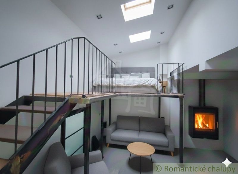 Interior of a family house with a gallery, sofa, fireplace, and bed on the upper floor.