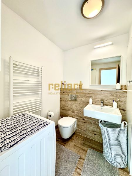 Bathroom in a studio apartment with a mirror, washing machine, and sink with wooden decor.