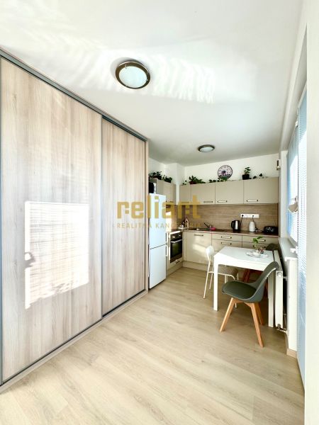 A kitchen corner with a wooden decor floor and a built-in wardrobe in a studio apartment.