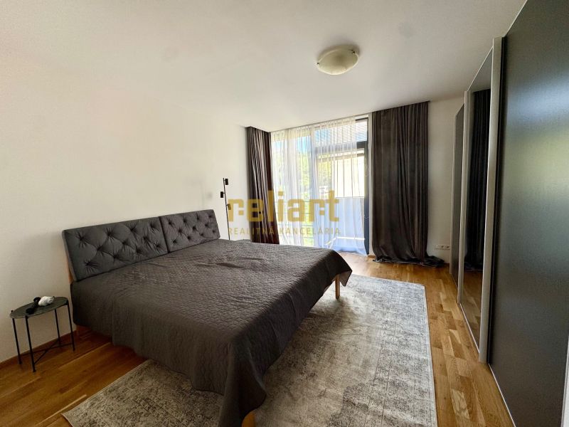 Bedroom in a 4-room apartment with wood-patterned flooring, a large bed, and a wardrobe.