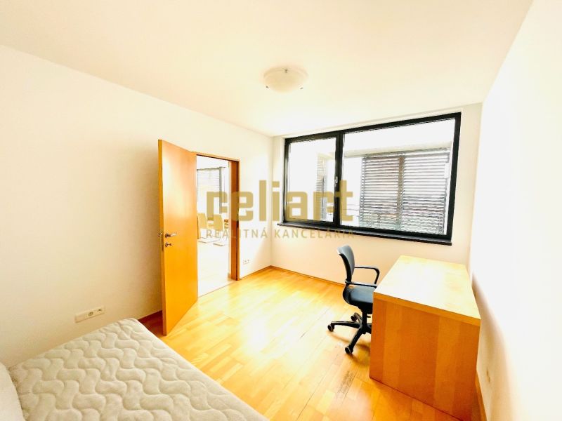 A room in a 4-room apartment with a wooden decor floor, a desk, and a chair.