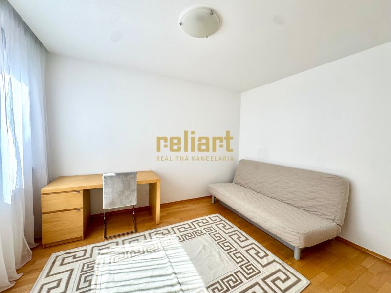 A room with a light sofa, a desk, and a wooden decor floor in a 4-room apartment.