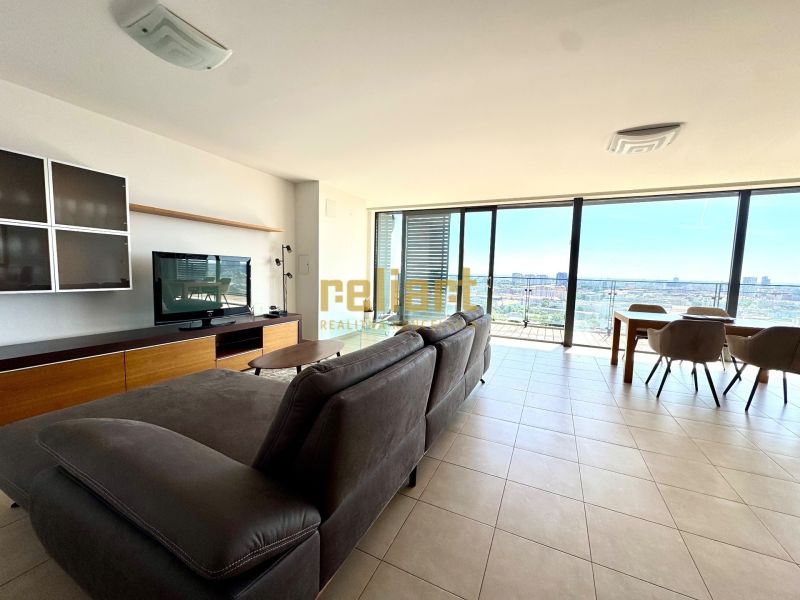Bright living room with a sofa, TV, and large windows, 4-room apartment.