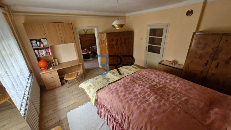 A bedroom in a family house with wooden decor and antique furniture.