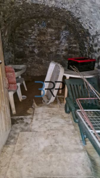 The stone cellar of a family house in Mokré Háj with stored furniture and crates.