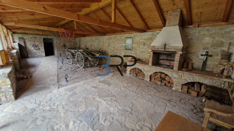 Covered seating area with a fireplace and stones in a family house, with a traditional cart and wood.