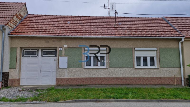 A family house in Mokrý Háj with a red roof and garage doors.