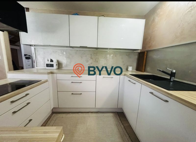 A kitchen in a 3-room apartment with white cabinets and a wooden decor countertop.