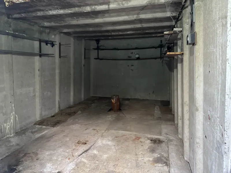 Concrete garage in Bratislava - Nové Mesto with simple walls and storage shelves.